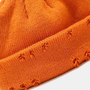Close-up of distressed ripped texture on orange knitted beanie hat for street style