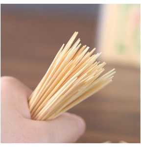 Close-up of a hand holding premium double-pointed bamboo toothpicks with sharp natural texture