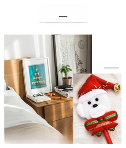 Détail d'un crayon décoratif de Noël avec tête en peluche, bonnet rouge et clochette