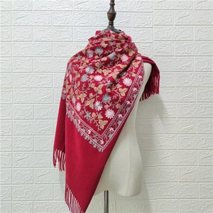 Close-up of red cashmere-feel shawl with detailed floral embroidery and tassel fringe edges
