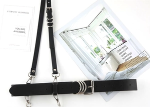 Flat lay of black PU leather body harness with silver metal buckles and ring details
