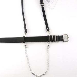 Detail of black faux leather body harness featuring silver rings and decorative metal chain