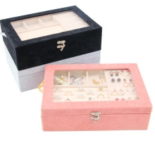 Macro shot of velvet jewelry boxes with glass lids in pink, black, and grey colors