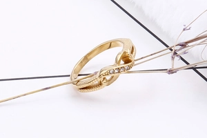 Detail of gold infinity knot ring with sparkling zircon stones and textured metal finish