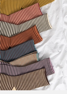 Flat lay of colorful striped cotton crew socks in eight diverse shades on a white fabric