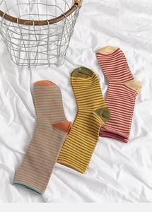 Detailed knit texture of three pairs of striped cotton crew socks on white fabric