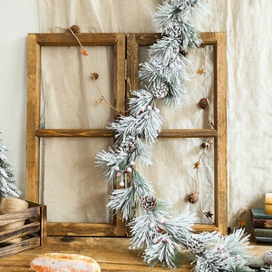 Snowy Christmas garland with pine cones and berries on a rustic vintage wooden window