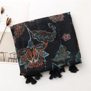 Détail d'une écharpe en lin bleu marine avec motifs floraux, paillettes et pompons noirs