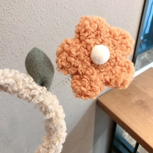 Detail of soft teddy fleece headband featuring a cute orange flower on a metal spring