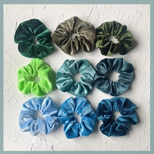 Nine colors of velvet scrunchies in green and blue tones displayed on a white background