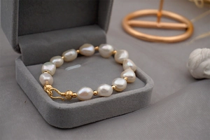 Detailed close-up of Baroque freshwater pearl bracelet with gold beads in a velvet jewelry box