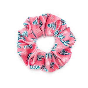 Pink velvet Christmas scrunchie with blue tree and white snowflake patterns on white background