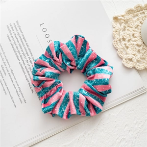 Detailed view of pink and green velvet scrunchie with polka dots on a stylish magazine