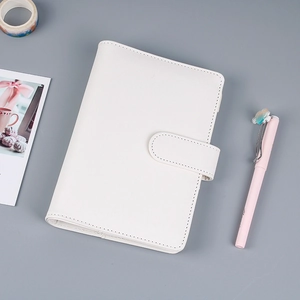 Vista plana de cuaderno de anillas de cuero sintético blanco con hebilla y bolígrafo rosa