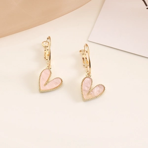 Pink heart pendant earrings with gold hooks on a minimalist cream background