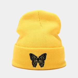Close-up of black butterfly embroidery on a bright yellow ribbed knit beanie hat