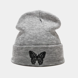 Close-up of grey knitted beanie featuring detailed black butterfly embroidery on the cuff