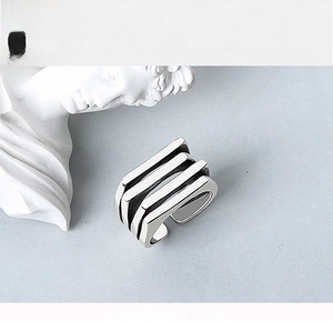 Detail of silver multi-layer open ring with three parallel lines on textured stone