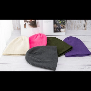 Flache Darstellung farbiger Strickmützen in Beige, Rosa, Grau, Grün und Lila auf Holz