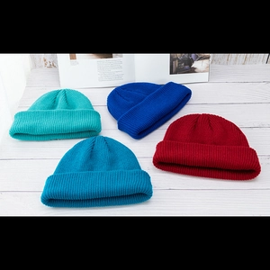 Flache Ansicht farbenfroher Strickmützen in Blau und Rot auf weißem Holzdekor