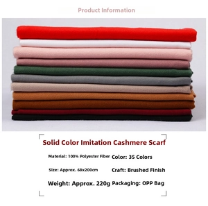 Detailed view of stacked solid color cashmere-like scarves with soft fringe and thick texture