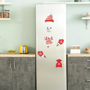 Close-up of magnetic snowman fridge decals including hat, scarf and carrot nose on silver metal
