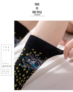 Detail view showing elastic cotton fabric and Evil Eye pattern on black mid-tube socks