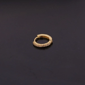 Gros plan d'une boucle d'oreille créole dorée avec des pierres de zircone cubique