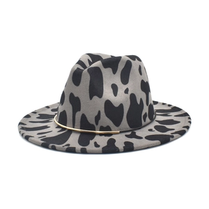 Close-up of cow print fedora hat featuring a gold metal band detail and wool texture