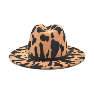 Brown wide brim jazz fedora with black cow print pattern and golden feather detail