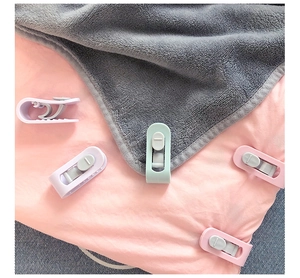 Detail showing macaron color needle-free duvet clips on soft fabric bedding
