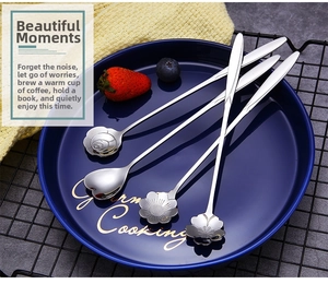 Macro shot of 4-piece floral stainless steel spoons on a blue plate with fresh berries
