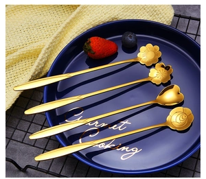 Detail of four golden stainless steel flower and heart shaped coffee dessert spoons