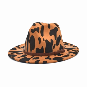 Dettaglio cappello fedora stile western con stampa mucca e sottile cintura in pelle marrone