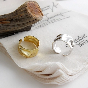 Detail view of irregular geometric rings in gold and silver finish on rustic background