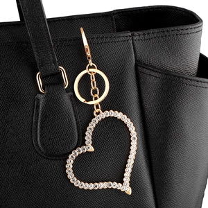 Détail d'un porte-clés coeur doré avec strass blancs sur un sac en cuir noir