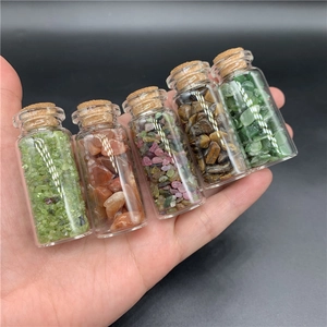 Close-up of five mini glass jars filled with natural healing gemstone chips held in hand