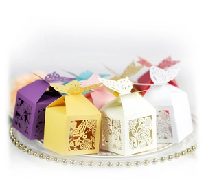 Laser-cut hollow butterfly wedding favor boxes in various colors on a white tray