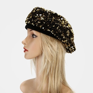 Detail of a black beret with dense gold sequins and wide brim, shiny party hat