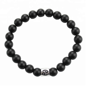 Detail of 8mm matte black stone bead bracelet featuring silver Cancer zodiac sign charm