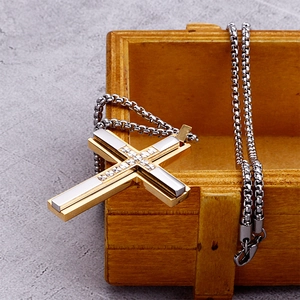 Detail of two-tone stainless steel cross pendant on a silver box chain over wood