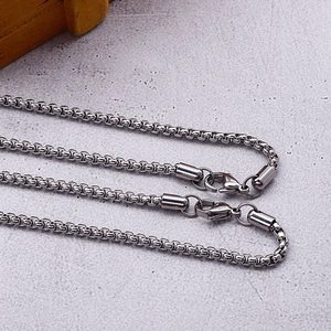 Macro detail of silver stainless steel box chain necklace with lobster clasp