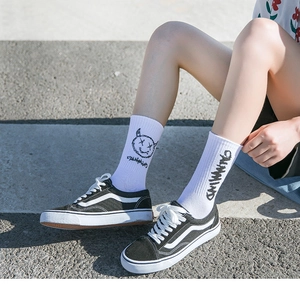 Détail de chaussettes en coton blanc avec texte graffiti noir et motif visage de démon