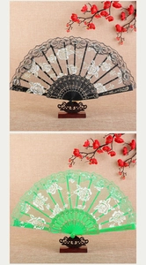 Detailed view of rose lace folding fans in black and green with vintage floral background