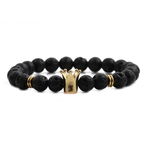 Macro shot of black volcanic lava stones and golden crown charm on a men's bracelet