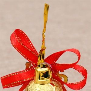 Macro detail of golden Christmas bell with a red bow and festive gold ribbon accent