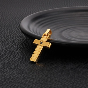 Minimalist gold stainless steel cross pendant with black gemstone on a textured background