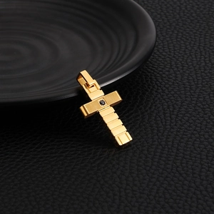 Close-up of golden cross pendant with black gemstone on textured leather surface