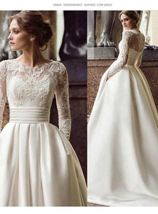 Detail of elegant long sleeve lace bodice and smooth satin skirt on a bridal wedding gown