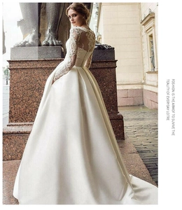 Detailed view of white bridal dress featuring intricate lace bodice and open back design